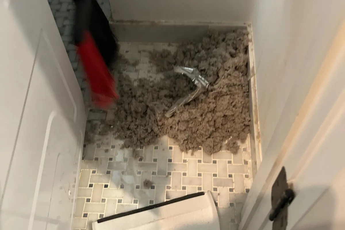 Pile of lint cleaned out of a dryer vent, on a tiled floor